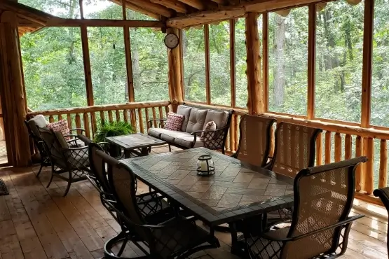 A long table surrounded by chairs on a screened in deck
