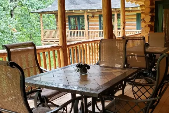 Table surrounded by chairs on a raised deck overlooking trees