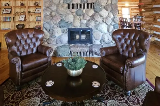 Two leather arm chairs by a fire with a circular table in between