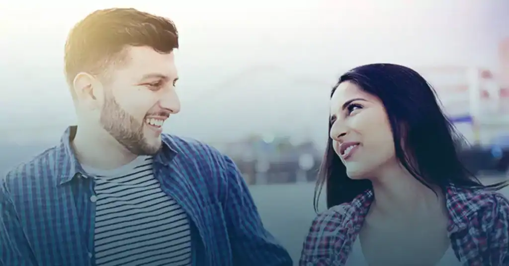 Smiling couple looking at each other outdoors with city background