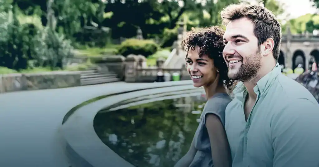 Happy interracial couple by decorative water feature in park setting